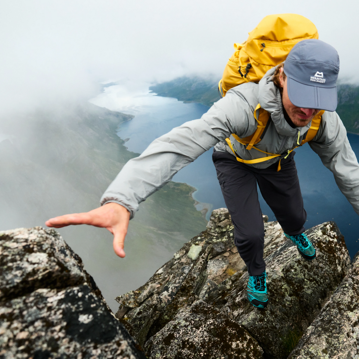 Ein Bergsteiger, der die graue Softshelljacke Aerotherm von Mountain Equipment beim Klettern über einem Fjrod in Norwegen trägt.