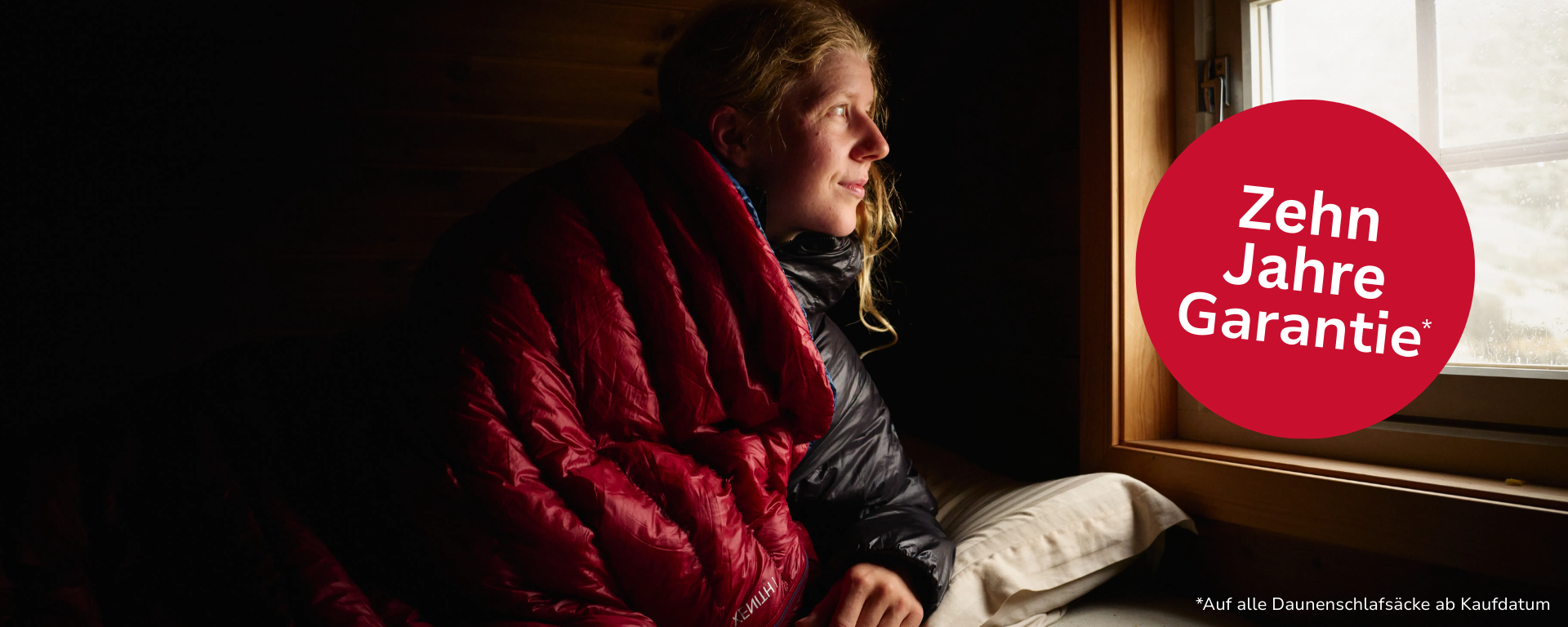 Eine junge Frau in einem roten Mountain Equipment Schlafsack.