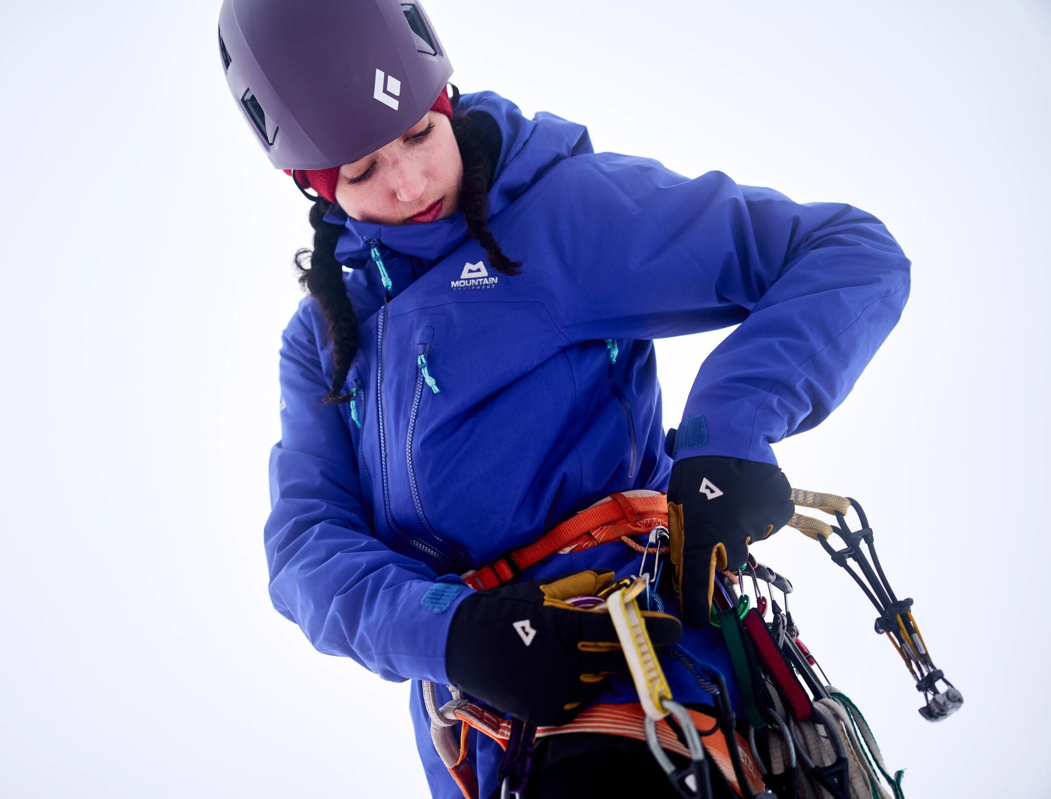 Eine junge Bergsteigerin mit blauer Tupilak Hardshelljacke von Mountain Equipment. 